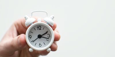 person holding white mini bell alarmclock